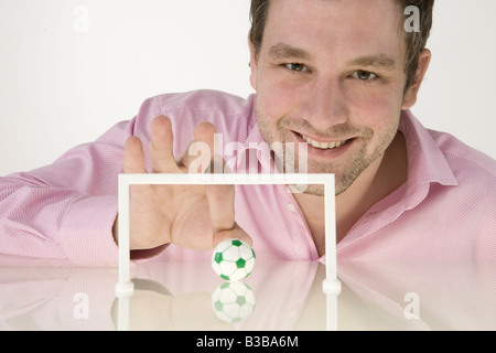 Geschäftsmann mit Miniatur-Fußball spielen Stockfoto