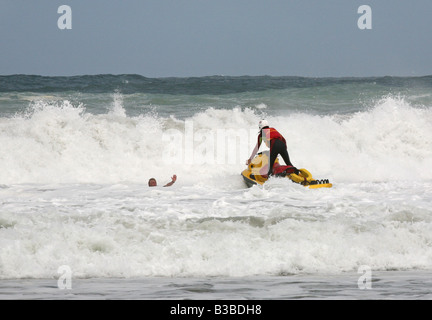 RNLI Rettungsschwimmer auf einem Jet Ski bewirkt eine Rettung in großen Surf aus St. Agnes, Cornwall, UK Stockfoto