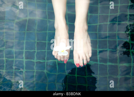 Womans Füße Schwimmen im Pool mit Blume in Zehen Stockfoto