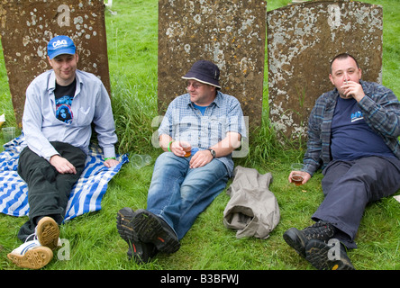 drei Männer trinken auf dem Friedhof in Cropredy Dorf zum Zeitpunkt der 2008 Fairport Cropredy Convention Stockfoto