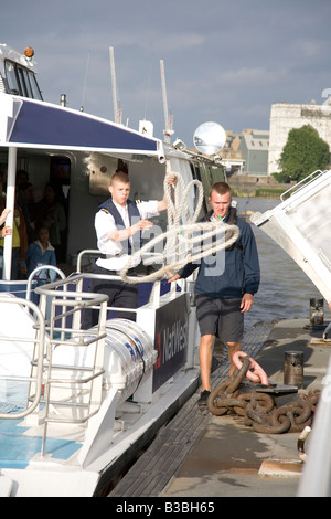 ein Mitglied der Crew von der Thames Clipper Personenverkehr auf dem Fluss Themse London wirft ein Seil um das Boot zu sichern Stockfoto