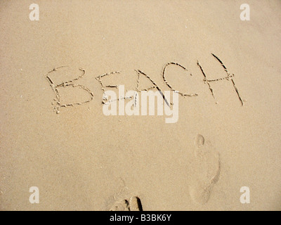 Das Wort Strand in den Sand zusammen mit ein paar Fußabdrücke geschrieben Stockfoto