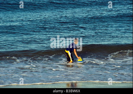 Junge spielt in Ocean Surf mit Spielzeug Boot, Cape Cod, Ma Stockfoto