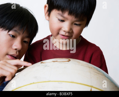 Asiatischen Brüder suchen im globe Stockfoto