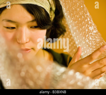 Asiatische Frau Luftpolsterfolie beiseite schieben Stockfoto