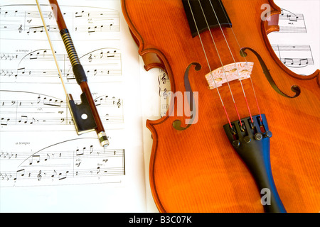 Dies ist eine Nahaufnahme von einer Geige und einer Schleife auf einem Notenblatt Stockfoto