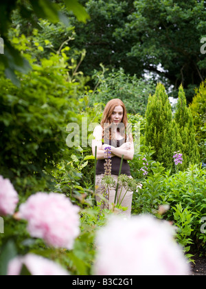 Eine Frau in einem Garten mit verschränkten Armen Stockfoto