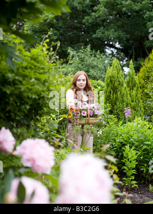 Eine Frau in einem Garten mit Korb mit Blumen Stockfoto