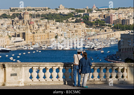 Malta, Valletta. Touristen suchen von einer eleganten auflehnen auf den alten Mauern von Valletta über den Grand Harbour in Richtung Vittoriosa. Stockfoto