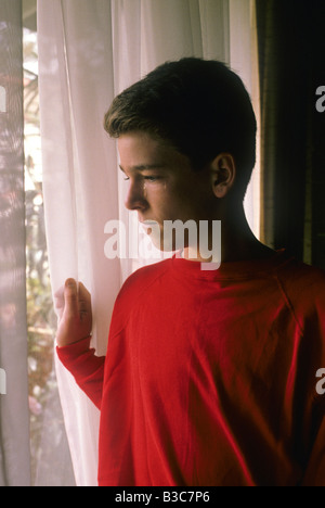 Porträt von teenboy am Fenster mit Tränen in den Augen Stockfoto