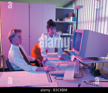 Geschäftsleute, die Blaupausen in Computer ansehen Stockfoto
