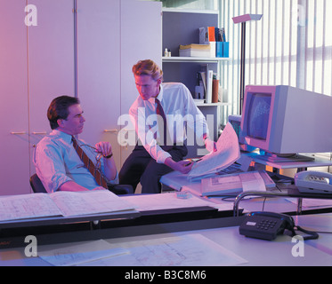 Geschäftsleute, die gerade Baupläne im Büro Stockfoto