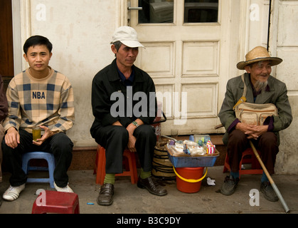 Drei vietnamesische Männer sitzen in einem provisorischen Restaurant vor einem Geschäft in Hanoi Vietnam Stockfoto