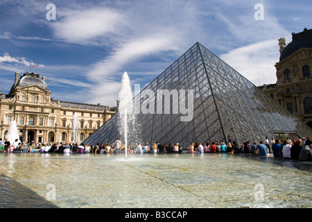 Menschen sitzen vor der Pyramide des Louvre in Paris, Frankreich Stockfoto