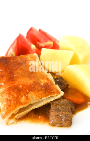 Ein Rind Steak Pie mit Blätterteig Kruste serviert mit gekochten Kartoffeln und Tomaten Keile Stockfoto