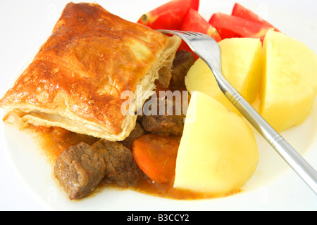 Ein Rind Steak Pie mit Blätterteig Kruste serviert mit gekochten Kartoffeln und Tomaten Keile Stockfoto