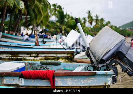 Angeln Pangas Beached Playa Principal Zihuatanejo | ZIHUATANEJO, Mexiko – Eine Reihe verwitterter Pangas sitzt am Playa Principal nach der Morgenlandung am Strand, Außenbordmotoren kippten nach oben und Kühler verzurrten immer noch an Bord. Diese kleinen offenen Boote bilden die Arbeitsflotte der ribereño von Zihuatanejo, oder kleine Küstenfischerei, die die Bucht und den schmalen Kontinentalsockel von Guerrero in kurzer Entfernung vom Strand bewirtschaftet. Stockfoto