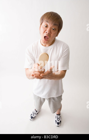 Mitte erwachsenen Mannes betrachten Haarbürste Stockfoto