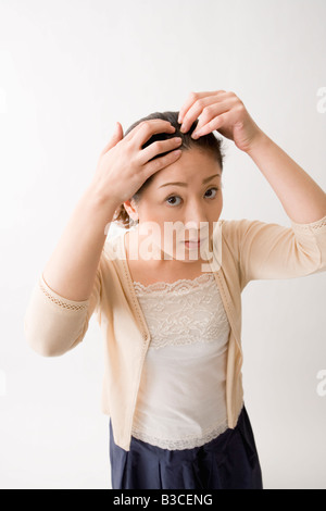Mitte Erwachsene Frau überprüfen ihr Haar Stockfoto