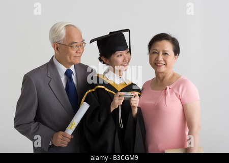 Junge weibliche Absolventin lächelnd mit ihren Eltern Stockfoto