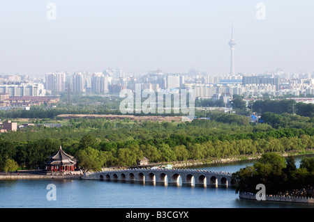 China, Peking. Sommer-Palast - UNESCO-Weltkulturerbe. Die 17 Bogenbrücke und die Skyline der Stadt. Stockfoto