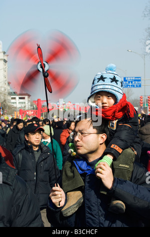 China, Peking. Chinesische neue Jahr Frühlingsfest - Changdian Straßenfest - ein Mann, der sein Kind mit einem Wind Vane Spielzeug trägt. Stockfoto