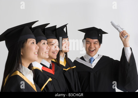 Junge männliche Absolventen Diplom und lächelnd mit seinen Freunden Stockfoto