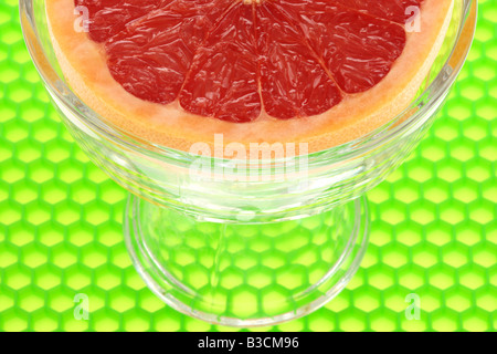 Frische reife Saftig eine halbe Frühstück Grapefruit In einer Schüssel mit keine Personen vor einem grünen Hintergrund Stockfoto