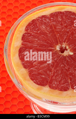 Frische reife Saftig eine halbe Frühstück Grapefruit In einer Schüssel mit keine Menschen auf rotem Hintergrund Stockfoto