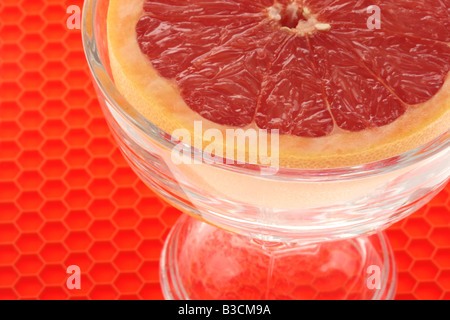 Frische reife Saftig eine halbe Frühstück Grapefruit In einer Schüssel mit keine Menschen auf rotem Hintergrund Stockfoto