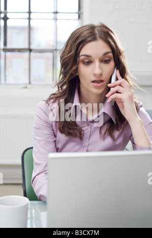 Junge Geschäftsfrau arbeiten am Laptop, Handy Stockfoto