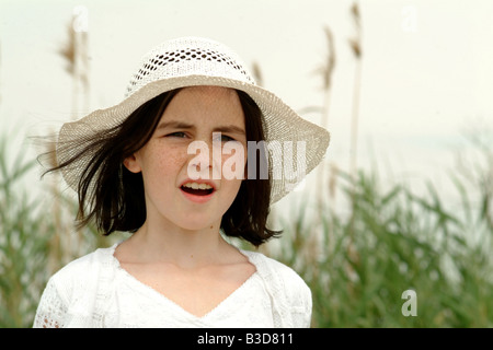 schönen 10 Jahre altes Mädchen in weißen Strohhut stehend durch eine Meadown im Sommer Stockfoto