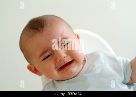 ein kleiner Junge weint, als er in seinem Hochstuhl sitzt Stockfoto