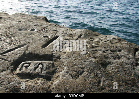 geschnitzte alte Initialen in Felsen an der Küste in Sonne Stockfoto