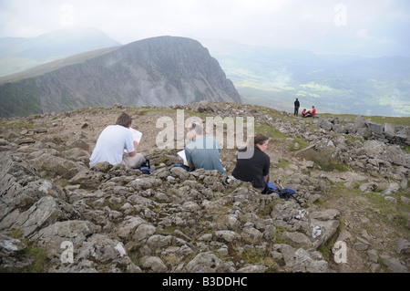 Cader Idris Kartenarbeit.  Drei Leute sitzen auf der Cairn auf Cader Idris in Nord-Wales. Stockfoto