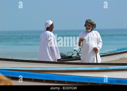 Zwei Männer tragen traditionelle Kleidung mit Angelboote/Fischerboote Sur Sharqiya Region Sultanat von Oman Stockfoto