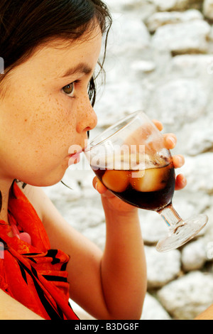 eine hübsche Brünette trinkt aus einem Glas Cola im Sommer Stockfoto