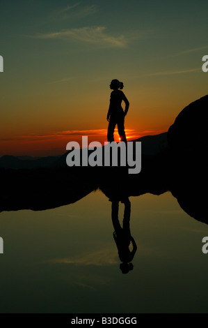 Mädchen spiegelt sich in einem See bei Sonnenuntergang, bei Litlefjellet, Romsdalen, Rauma Kommune, Norwegen. Stockfoto