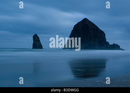 Sunrise und Meer-Stacks auf dem Strand in Cannon Oregon mit einem dramatischen Himmel im Hintergrund Stockfoto