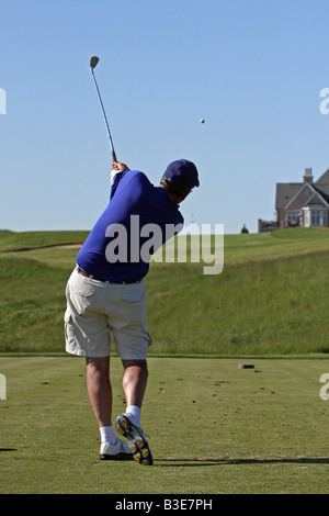 Golfer mit einem großen Golfschwung nach der Kollision mit seinem Abschlag an den Abschlag auf einem Par 3 bergauf durch folgende. Stockfoto