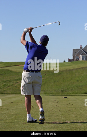 Golfer mit einem großen Golfschwung nach der Kollision mit seinem Abschlag an den Abschlag auf einem Par 3 bergauf durch folgende. Stockfoto