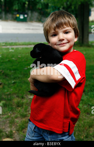 Kleiner Junge auf dem Hof mit seinem schwarzen Labrador-Welpe Stockfoto
