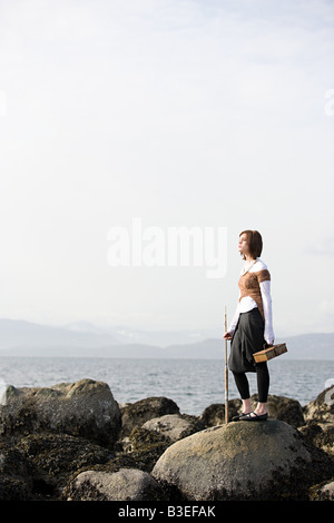 Junge Frau auf Felsen am Meer Stockfoto