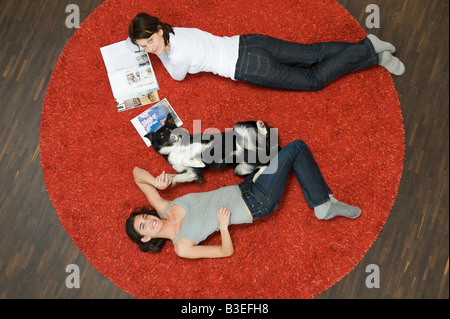 Frauen und Hund liegen auf Teppich Stockfoto