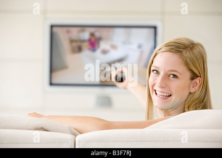 Frau im Wohnzimmer Fernsehen lächelnd beobachten Stockfoto