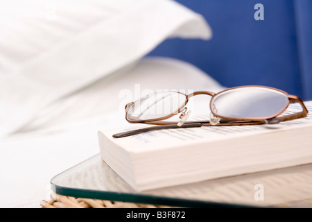 Leere Schlafzimmer mit Fokus auf Brille und Buch Stockfoto