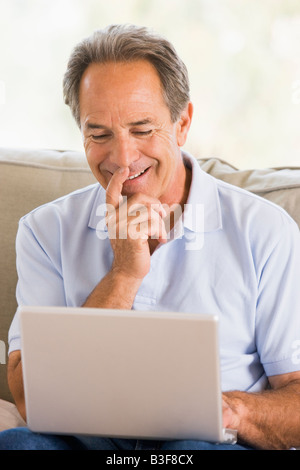 Mann im Wohnzimmer mit Laptop lächelnd Stockfoto
