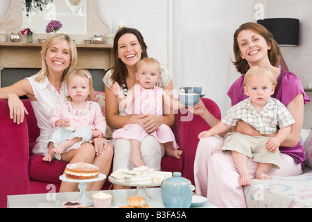 Drei Mütter im Wohnzimmer mit Babys und lächelnd Kaffee Stockfoto