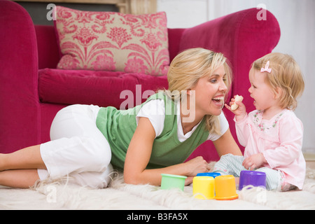 Mutter im Wohnzimmer mit Baby Banane essen und lächelnd Stockfoto