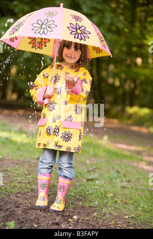 Junges Mädchen im Freien bei Regen mit Regenschirm lächelnd Stockfoto